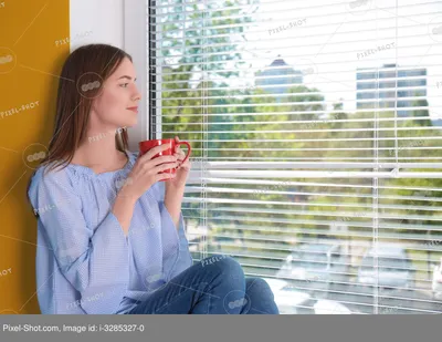 Красивая молодая девушка смотрит в окно и держит в руках чашку кофе или чая  :: Стоковая фотография :: Pixel-Shot Studio