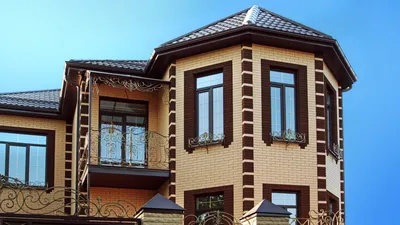 Дом желтого кирпича и коричневой рифлёной крыши сделанных из металла  Решетки на окнах Стоковое Изображение - изображение насчитывающей камин,  щипец: 101064467