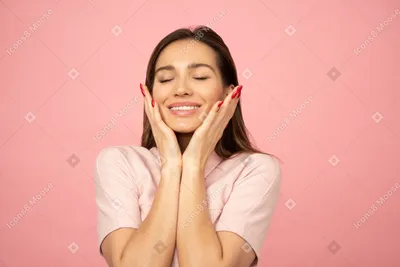 Фото Привлекательная молодая девушка улыбается и касаясь ее лица обеими  руками