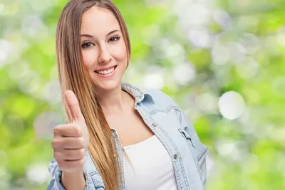 Фото Привлекательная молодая девушка улыбается и показывает большой палец  вверх
