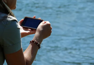 Девушка при мобильный телефон сидя на песке около моря Стоковое Фото -  изображение насчитывающей джинсыы, клетчато: 65697644