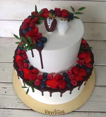 Двухъярусный свадебный торт с белым кремовым покрытием, потеки шоколада,  ягодами и парой клубничек