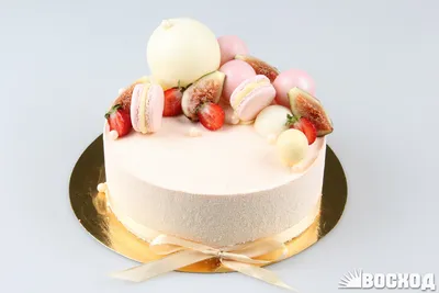 Круглый торт с покрытием гляссаж белого цвета, пирожными макарон и голубикой